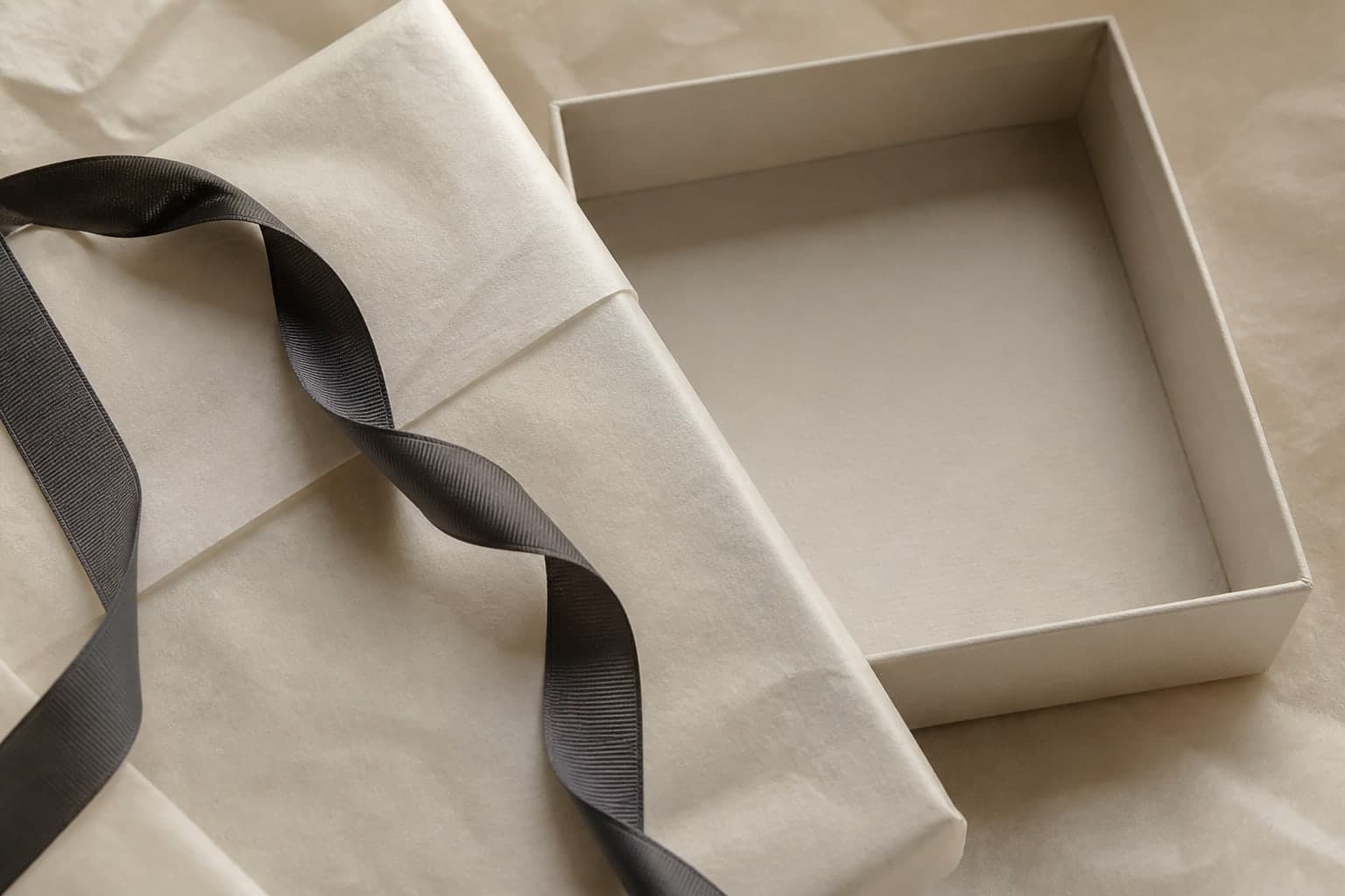 Open gift box with tissue paper and charcoal ribbon.